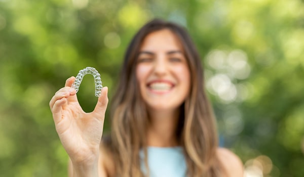 A young woman holding some aligners