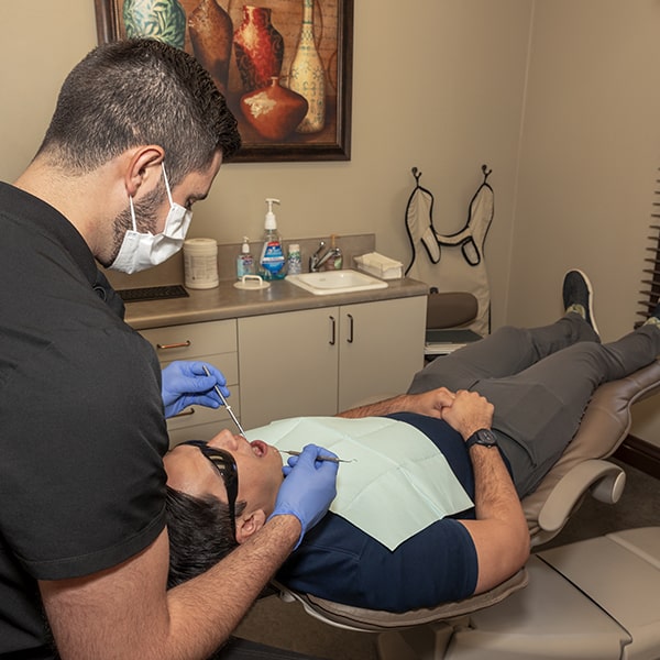 Dr. Marabeh checking the mouth of a patient who is lying in the dentist's chair