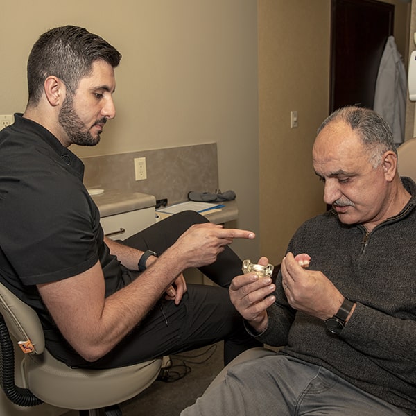 Dr. Marabeh explaining to an older man about dental implants