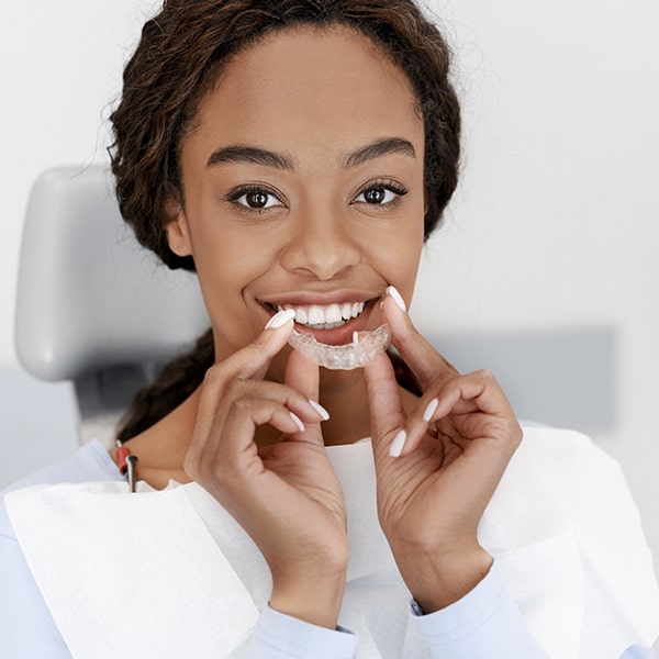 A woman sitting in the dentist's chair while having aligners fitted