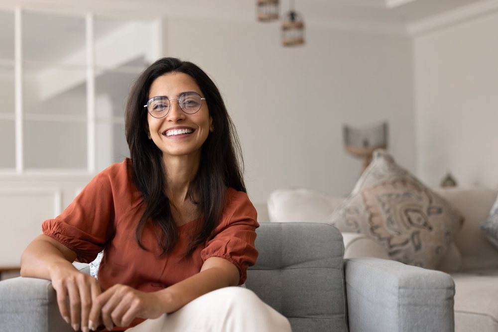 Smiling woman in glasses sitting on a sofa