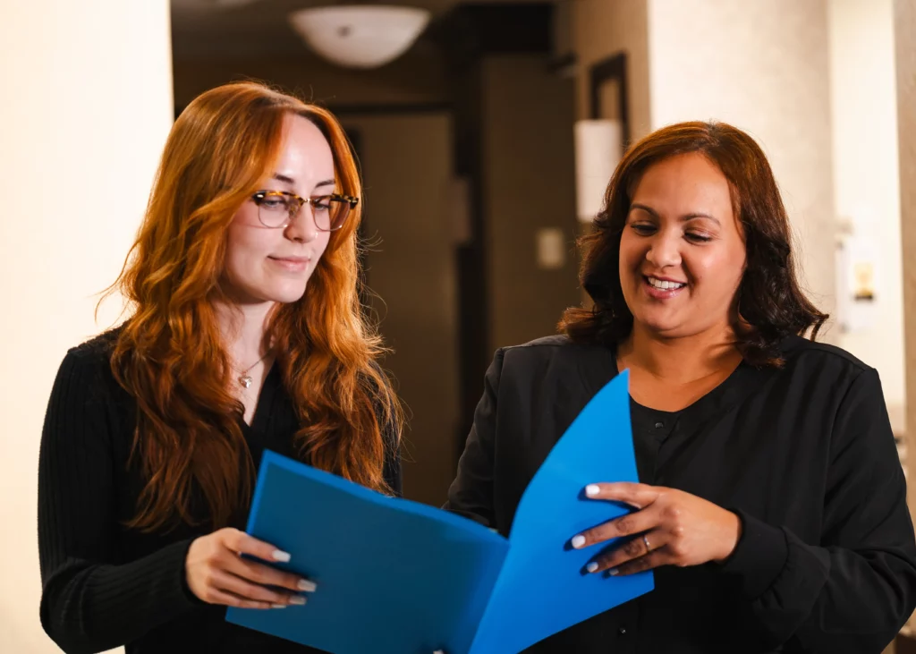 Two North County Dental Arts team members reviewing a blue patient folder together